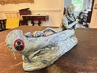 Full view of sculpture showing canoe, figure, red certification sticker