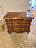 Front view showing three drawers, hardware, legs, overall style