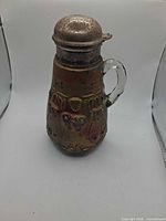 Front view of pressed-glass pitcher with metal lid