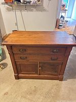 Front view showing two drawers with brass handles and lower cupboard doors