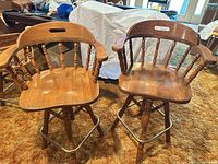 Two matching wooden swivel bar stools side by side