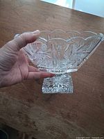Oblique view of flared cut glass bowl on pedestal held in hand