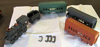 Entire train set laid out showing locomotive, tender, three cars and four hooks