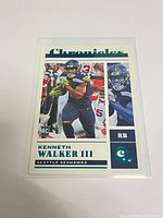 Front view of teal parallel Kenneth Walker III rookie card in sleeve