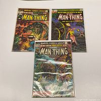 Three bagged Man-Thing comics laid out