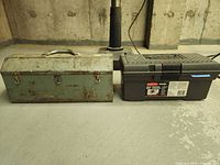 Closed green metal toolbox and black plastic toolbox side by side