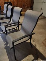 Four grey sling patio chairs, black metal frames