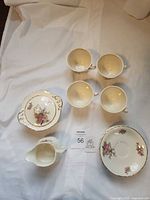 Full set laid out showing 4 cups, saucer, sugar bowl with lid and creamer