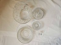 Four clear cut crystal pieces laid flat showing patterns and sizes