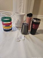 group shot of both pitchers, two travel mugs and stemless tumbler