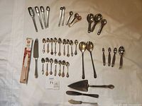 Entire lot laid out showing knives, servers, measuring spoons, souvenir spoons and servers