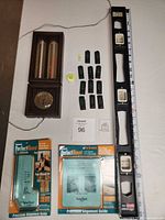 Group shot showing all items laid out: wood thermometer/hygrometer, long spirit level, two packaged PerfectMount guides, loose bubble levels