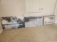 Three prints lined up against wall: two larger stretched canvas and one smaller framed