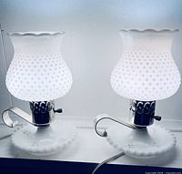 Two small hobnail milk glass lamps illuminated