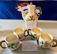 Coffee pot and four short mugs displayed