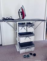 Full view of open ironing board cabinet with iron and casters