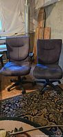 Front view of both blue upholstered rolling chairs showing one with arms and one without