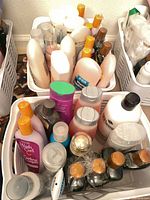 Three white baskets filled with assorted shampoo and conditioner bottles, oils and sprays