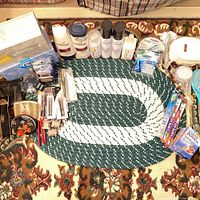 Entire lot overview on braided rug showing tissues, hair products, makeup, oral care, cotton rounds, toothbrushes