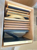 Box containing stacked picture frames of various finishes and sizes