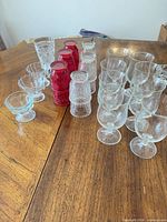 Overall view of clear and ruby red pressed glass goblets, tumblers, and sherbet cups on table