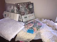 Overall lot with packaged curtains, floral valance, crocheted linens on dresser