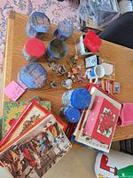 Overview of entire lot on table showing tins, ornaments, cards, mug, books