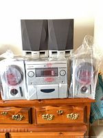 Front view of Audiologic main unit flanked by RCA speakers, all sealed in plastic
