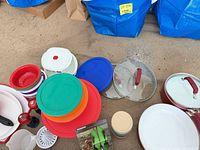 Overall view of stacked saucepans, lids, plates, bowls, grinders, juicer and storage jars