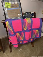 Full view of wooden blanket stand holding packaged Columbia throw, crochet blanket and patchwork quilt