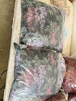 Two floral tapestry pillows in plastic bags on surface