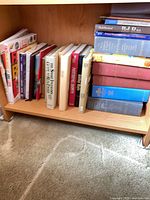 Books on lower bookshelf showing assorted titles and four large red/blue reference volumes