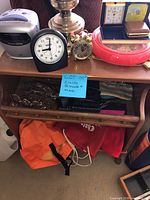 Shelf with clock radio, analog alarm clock, miniature rotary phone, eyeglass frames, bags