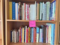 Two rows of assorted books on bookcase showing quantity and variety