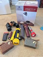 Group shot showing lamp box, binoculars, six flashlights, three portable radios