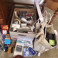 Cardboard box containing mixed light bulbs, fasteners, small tools, tape, video adapter and other hardware
