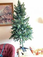 Full view of the assembled artificial tree on stand next to chair