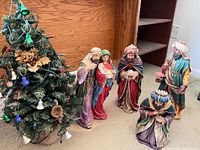 Nativity figurines positioned beside decorated artificial tree