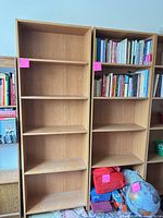 Front view of both tall light oak laminate bookcases showing shelf arrangement