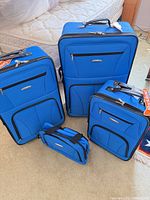 Front view of all four blue Rockland luggage pieces with tags visible