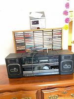 Front view of Sony CFD-444 boombox, detachable speakers, AC cord, wood cassette rack loaded with tapes