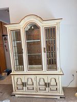 Full view of china cabinet showing upper glass doors, arched crown, lower storage doors