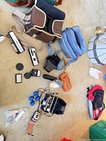 Overview of cameras, flashes, bags and accessories spread on carpet