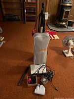 Aerus Lux Lite upright vacuum, Bissell handheld, wand and box of attachments on floor