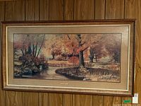 Full view of framed autumn landscape print on wood-panel wall