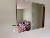 Front view of rectangular mirror mounted on wall showing reflection and corner clips