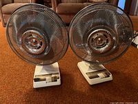 Front view of both Sears oscillating table fans standing on carpet