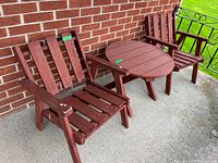 Full view of two wooden armchairs and round table against brick wall