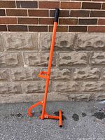 Full view of orange steel timber jack with foot stand and hook