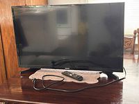 Front view of Samsung 32-inch Smart LED TV on table with remote and power cord
